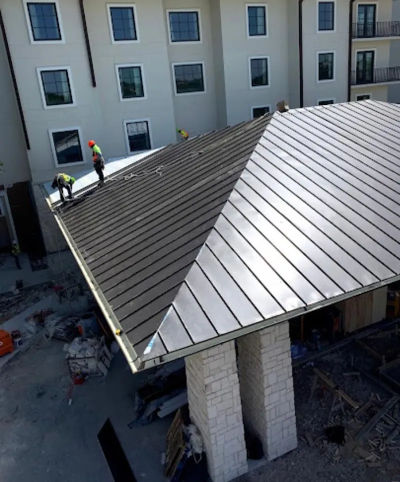 Crew installing standing seam metal roof panels on a commercial project in Deschutes River Woods